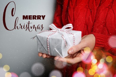 Merry Christmas. Woman holding gift box on grey background, closeup