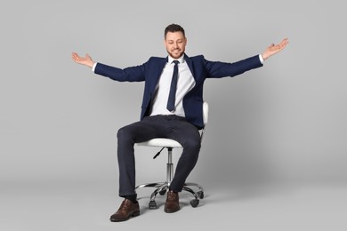 Handsome businessman sitting in office chair on grey background