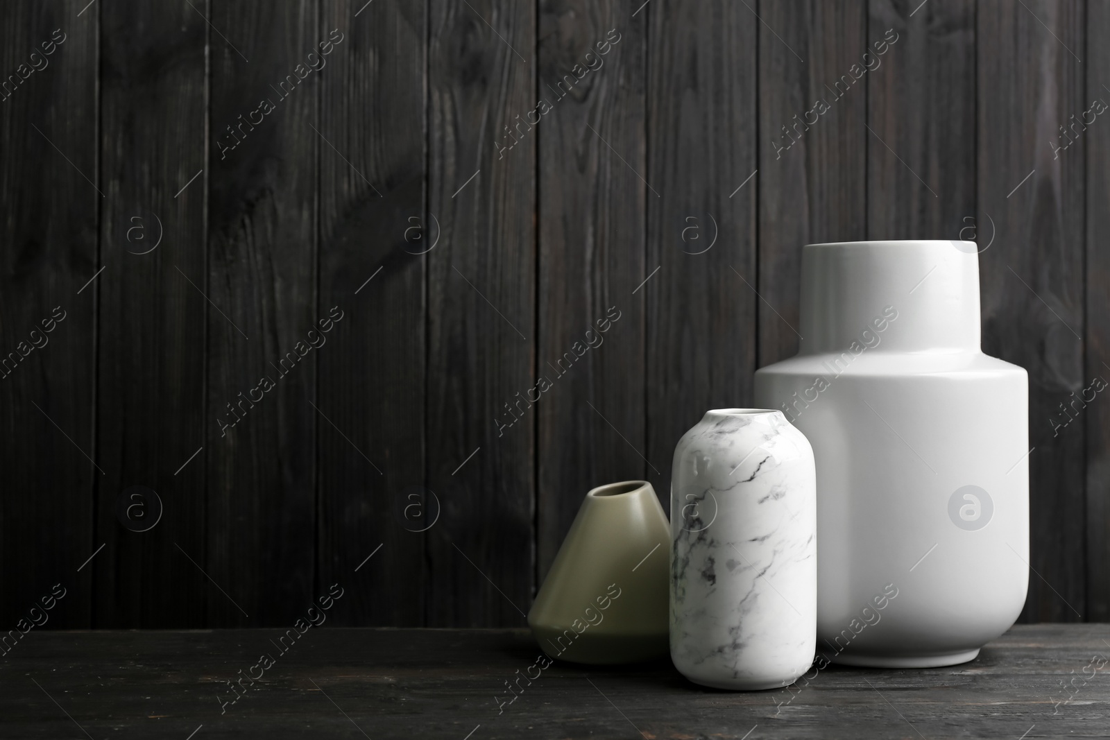 Photo of Stylish ceramic vases on black wooden table. Space for text