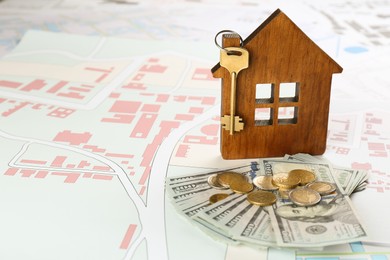 Photo of Money and wooden house model with key on cadastral map
