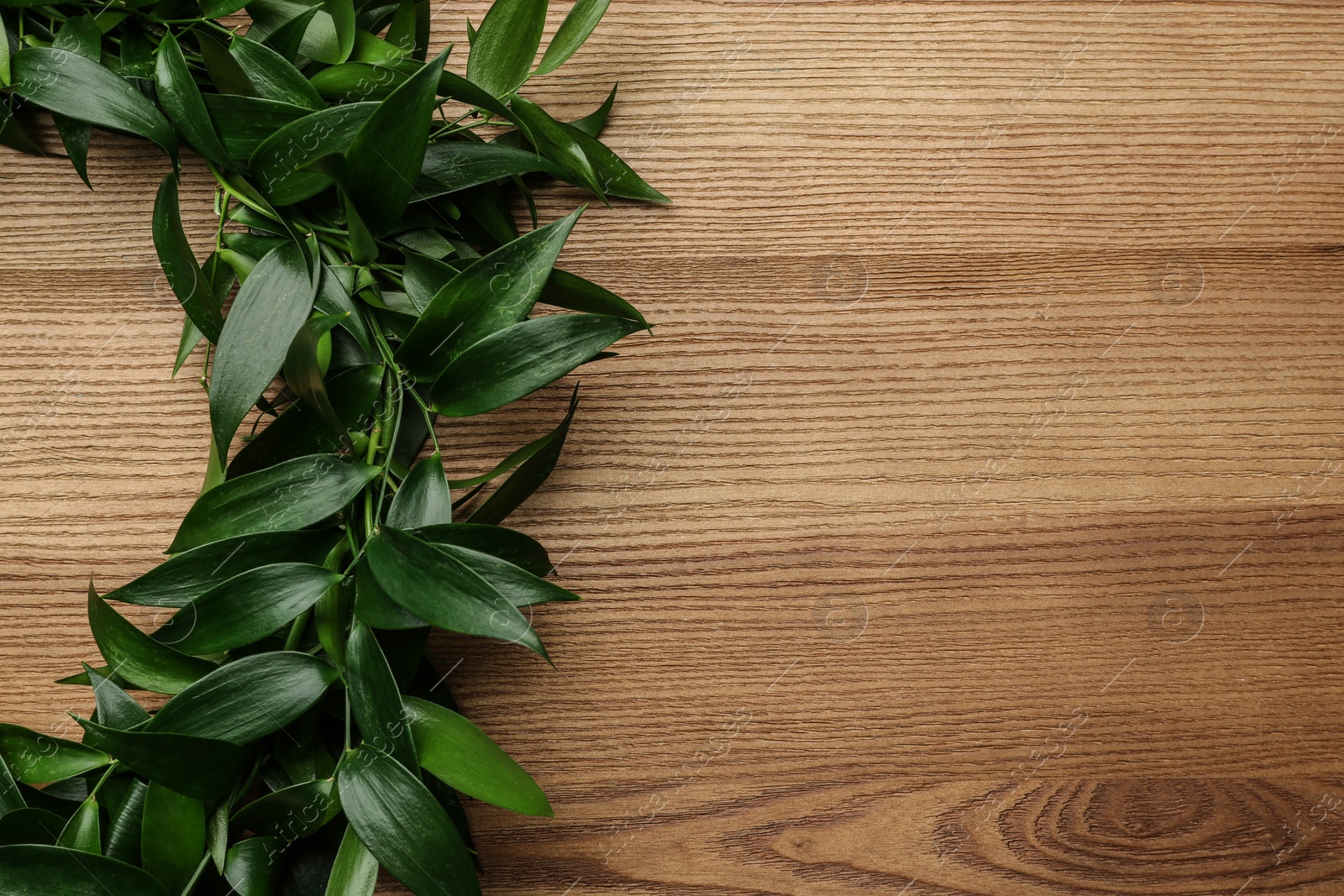 Photo of Beautiful handmade mistletoe wreath on wooden table, top view. Space for text