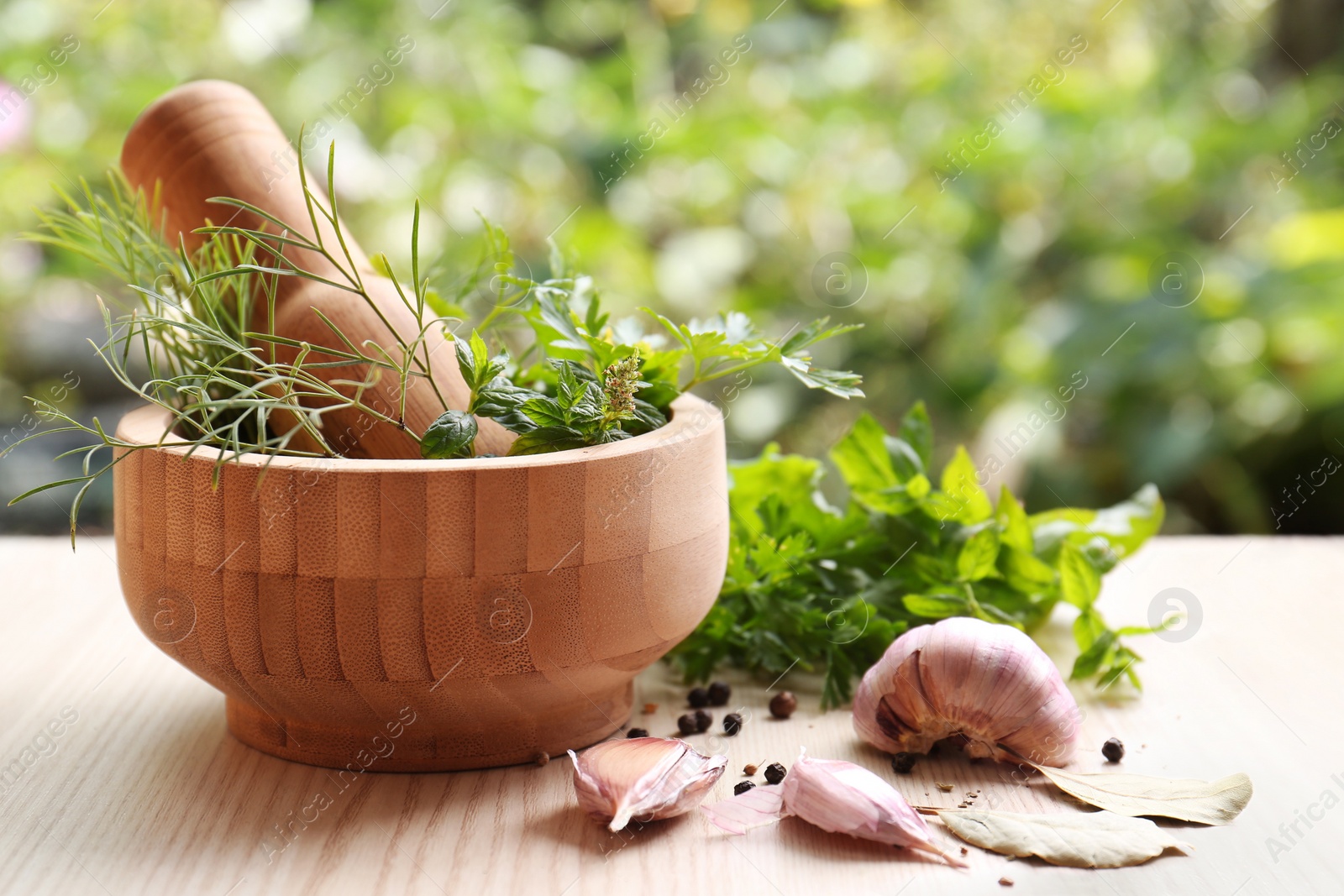 Photo of Mortar with pestle and different ingredients on wooden table outdoors