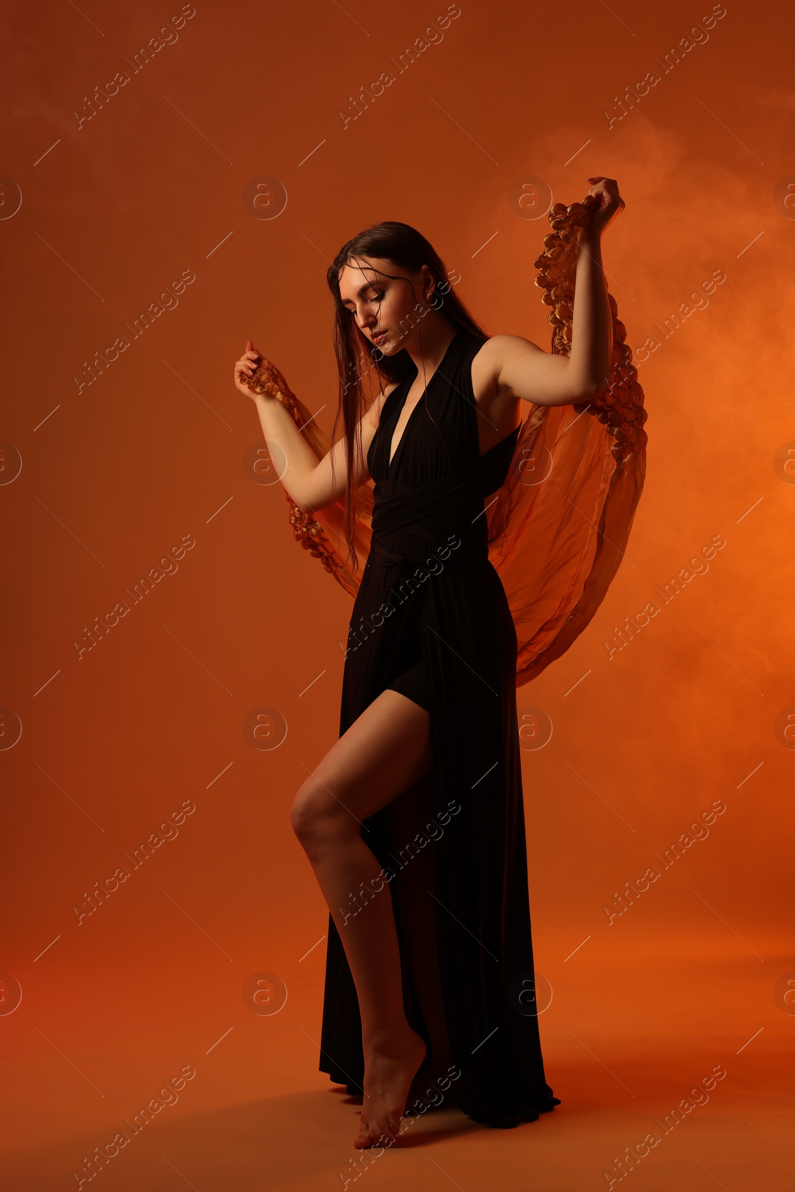 Photo of Beautiful woman in black dress and shawl posing on brown background