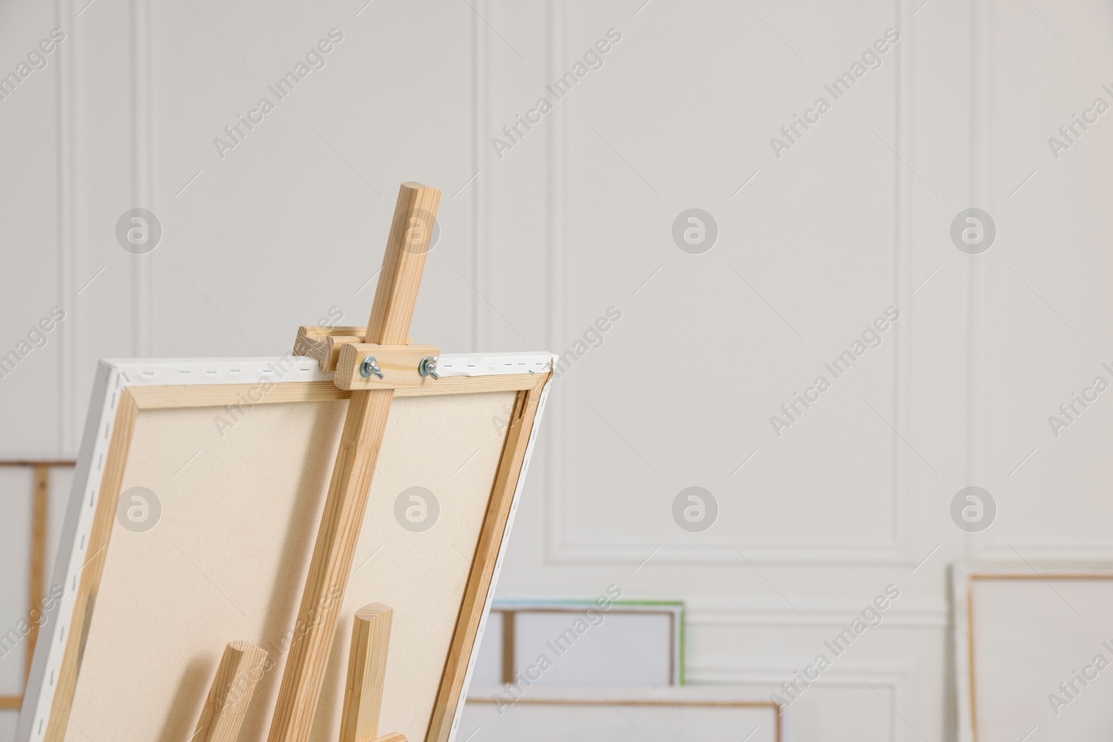 Photo of Wooden easel with canvas in artist's studio, space for text