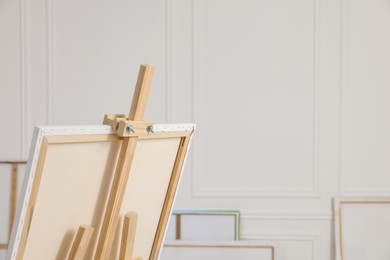 Wooden easel with canvas in artist's studio, space for text