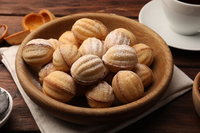 Photo of Delicious nut shaped cookies with boiled condensed milk and powdered sugar on wooden table, closeup