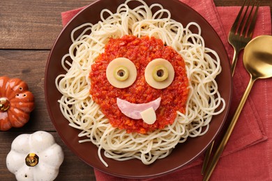 Plate with funny monster made of tasty pasta served on wooden table, flat lay. Halloween food