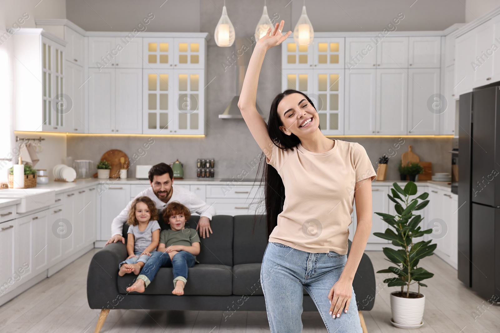 Photo of Happy family having fun at home. Mother dancing while her relatives resting on sofa