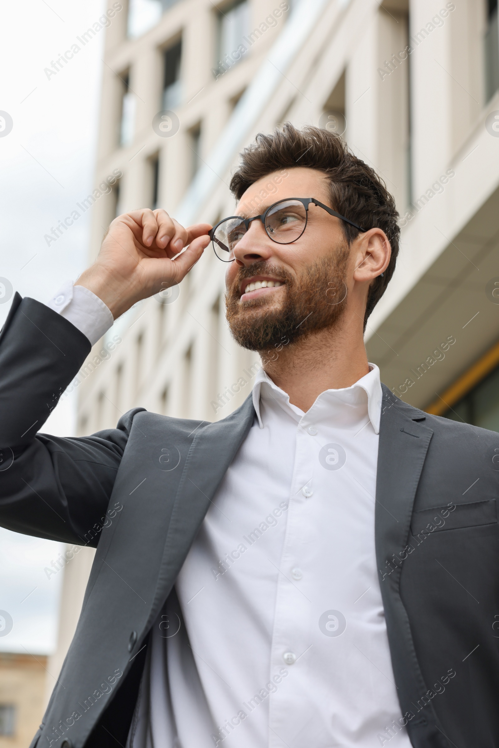 Photo of Handsome bearded businessman in eyeglasses near building outdoors