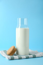 Glass carafe of fresh milk and lid on light blue background