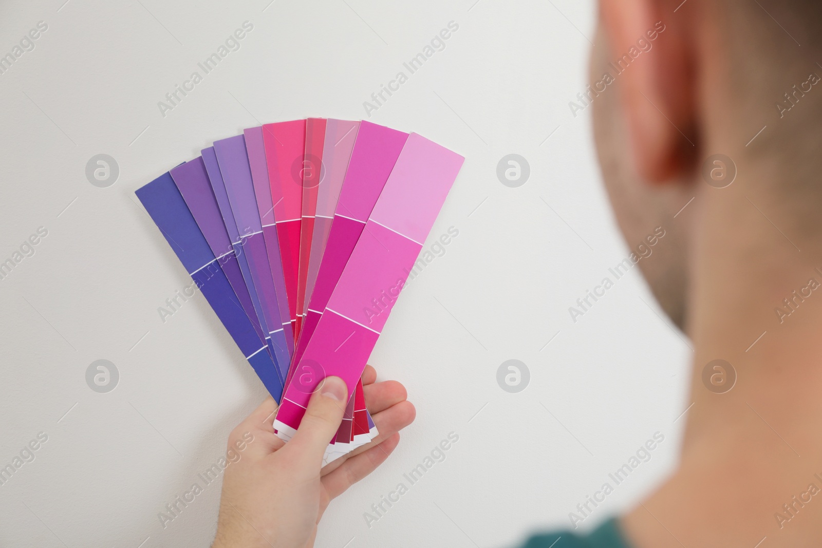 Photo of Man with palette choosing color for painting wall indoors, closeup. Interior design