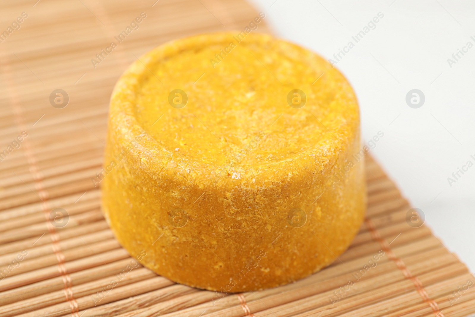 Photo of Yellow solid shampoo bar on light table, closeup