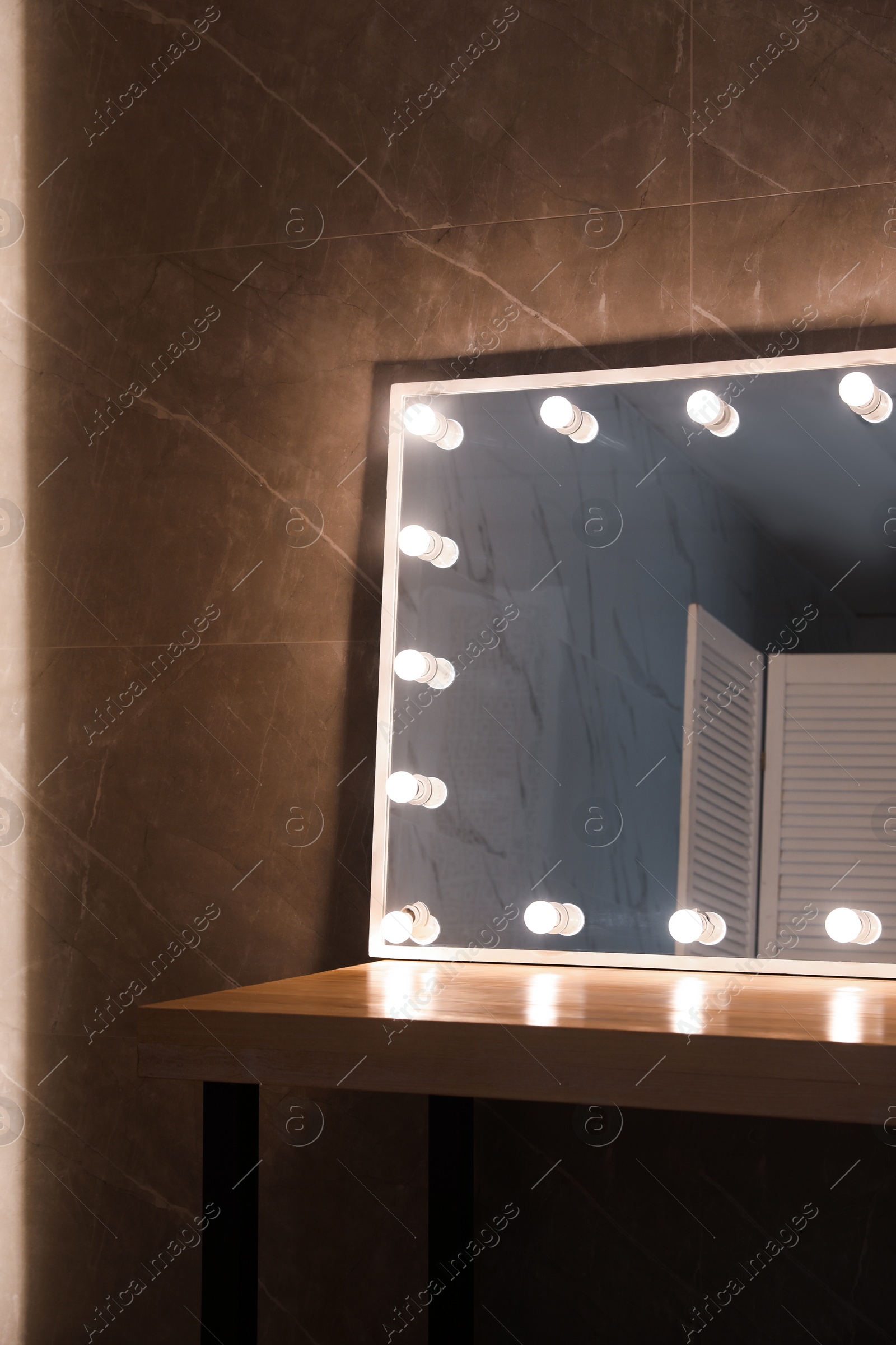 Photo of Modern mirror with light bulbs on wooden table in room