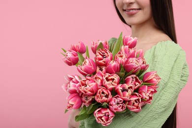 Happy woman with beautiful bouquet on dusty pink background, closeup