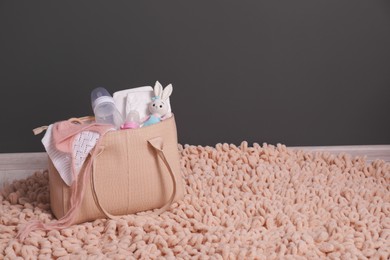 Photo of Mother's bag with baby's stuff on rug indoors