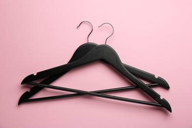 Photo of Black hangers on pink background, top view