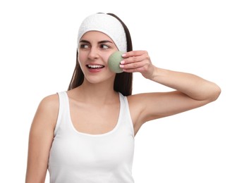 Photo of Young woman with headband washing her face using sponge on white background