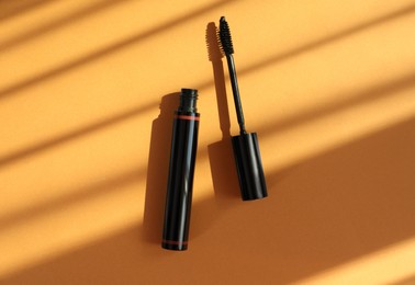 Mascara for eyelashes on orange background, flat lay. Makeup product