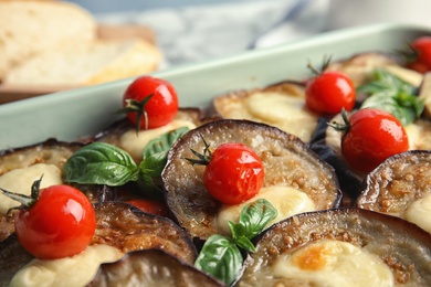 Photo of Baked eggplant with tomatoes, cheese and basil in dishware, closeup