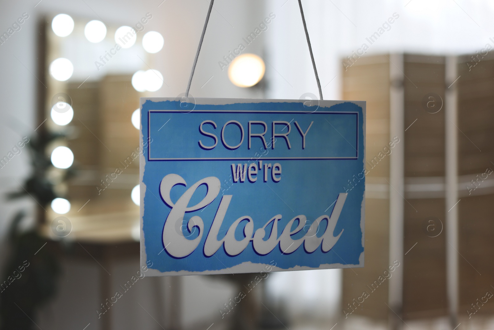 Photo of Light blue sign with text Sorry we're Closed hanging on glass door. Coronavirus quarantine