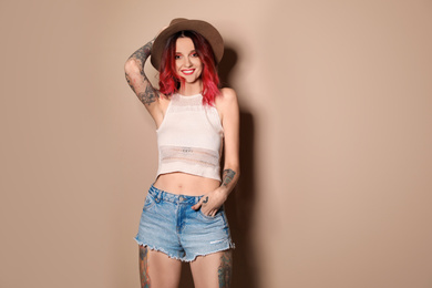 Photo of Beautiful woman with tattoos on body against beige background. Space for text