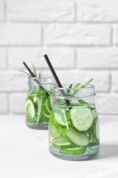 Photo of Natural lemonade with cucumber and rosemary in jars on table