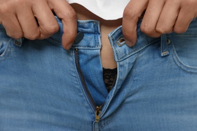 Photo of Woman trying to put on tight jeans, closeup