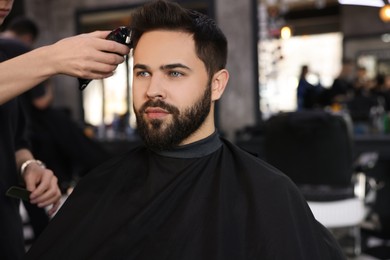 Photo of Professional hairdresser working with client in barbershop