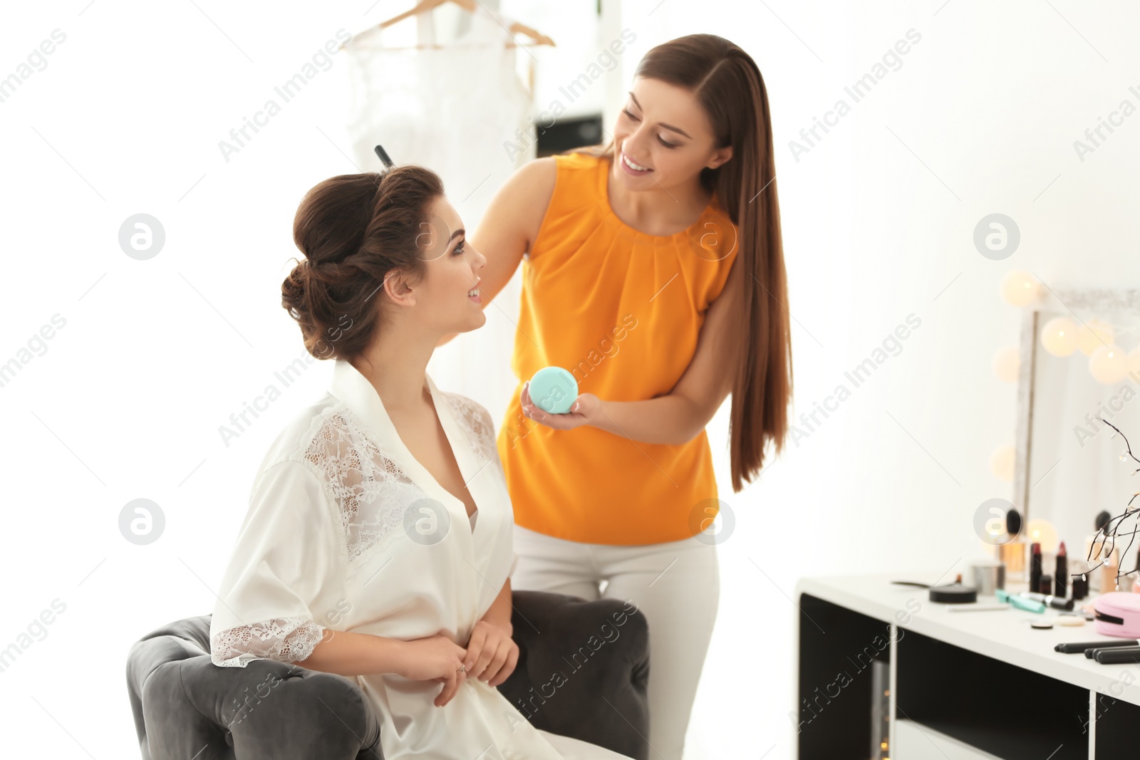 Photo of Makeup artist preparing bride before her wedding in room