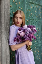 Photo of Beautiful woman with bouquet of spring flowers near building outdoors