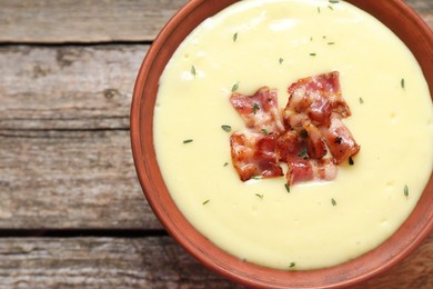 Photo of Tasty potato soup with bacon and rosemary in bowl on wooden table, top view. Space for text