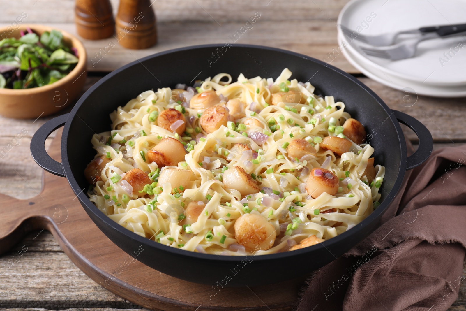 Photo of Delicious scallop pasta with onion in pan on table, closeup