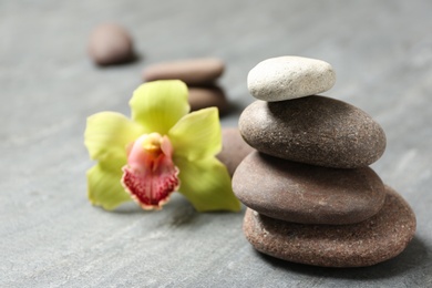 Stacked spa stones with flower on grey table. Space for text