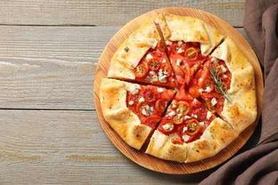 Photo of Tasty galette with tomato, rosemary and cheese (Caprese galette) on wooden table, top view. Space for text