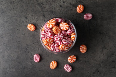 Photo of Colorful hard candies in glass jar on dark table, flat lay