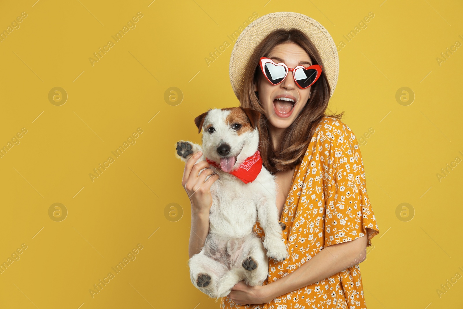 Photo of Young woman with her cute Jack Russell Terrier on yellow background. Lovely pet