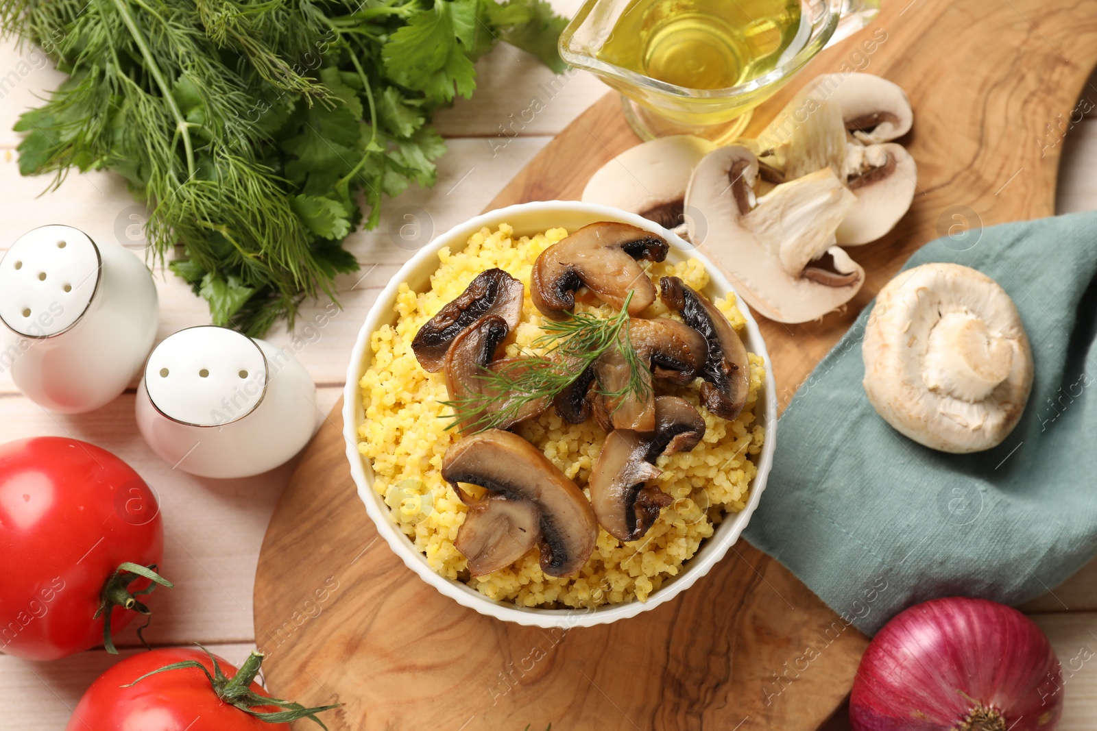 Photo of Tasty millet porridge, mushrooms and dill in bowl on light wooden table, flat lay