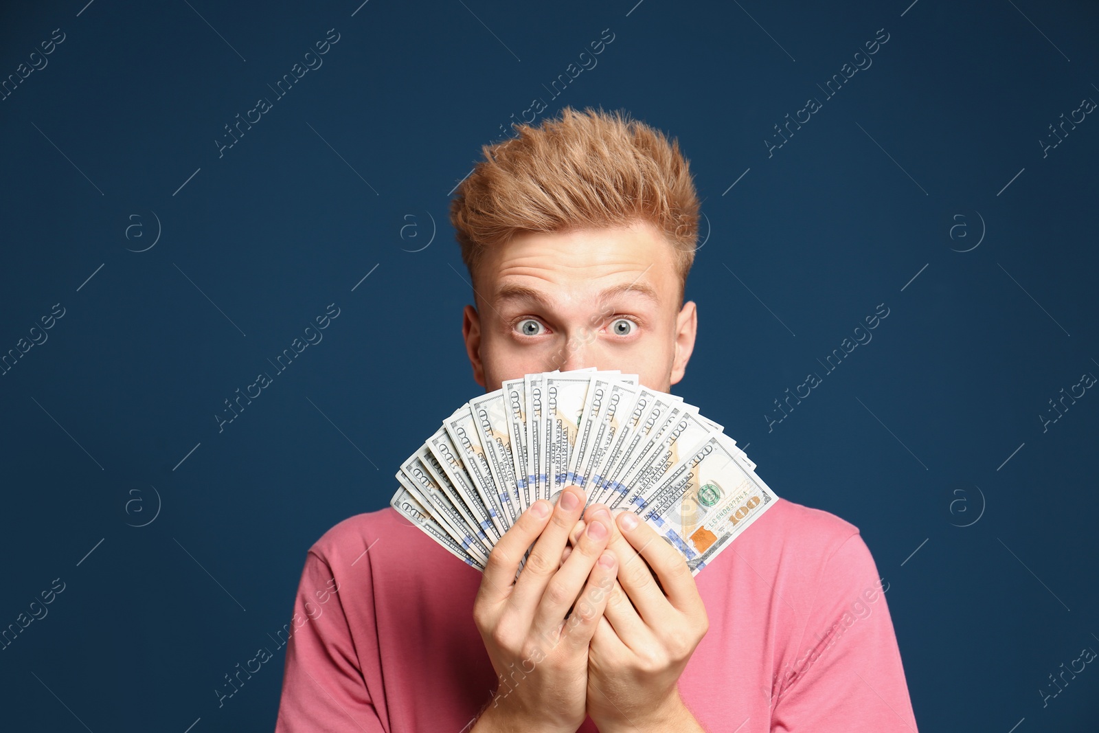 Photo of Portrait of surprised lottery winner with money fan on blue background