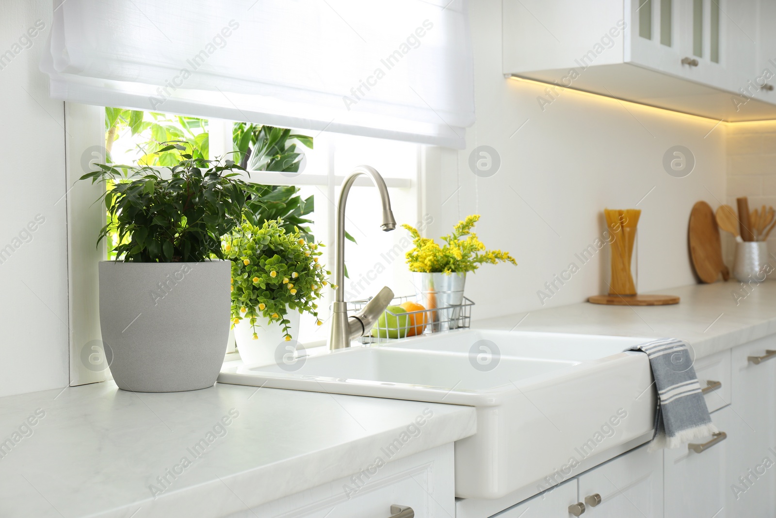 Photo of Beautiful white sink near window in modern kitchen