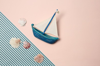 Flat lay composition with small boat and seashells on color background. Beach objects