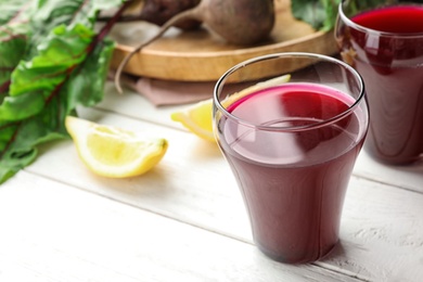 Photo of Glass of beet juice on white wooden table. Space for text