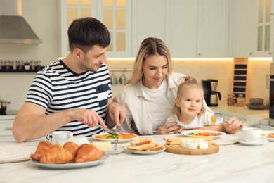 Photo of Happy family having breakfast together at table in kitchen