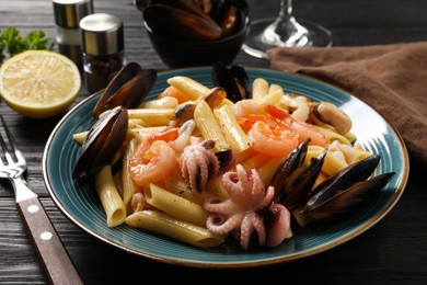 Photo of Delicious pasta with seafood served on black wooden table, closeup