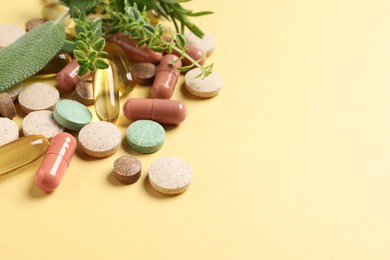 Photo of Different pills and herbs on light yellow background, space for text. Dietary supplements