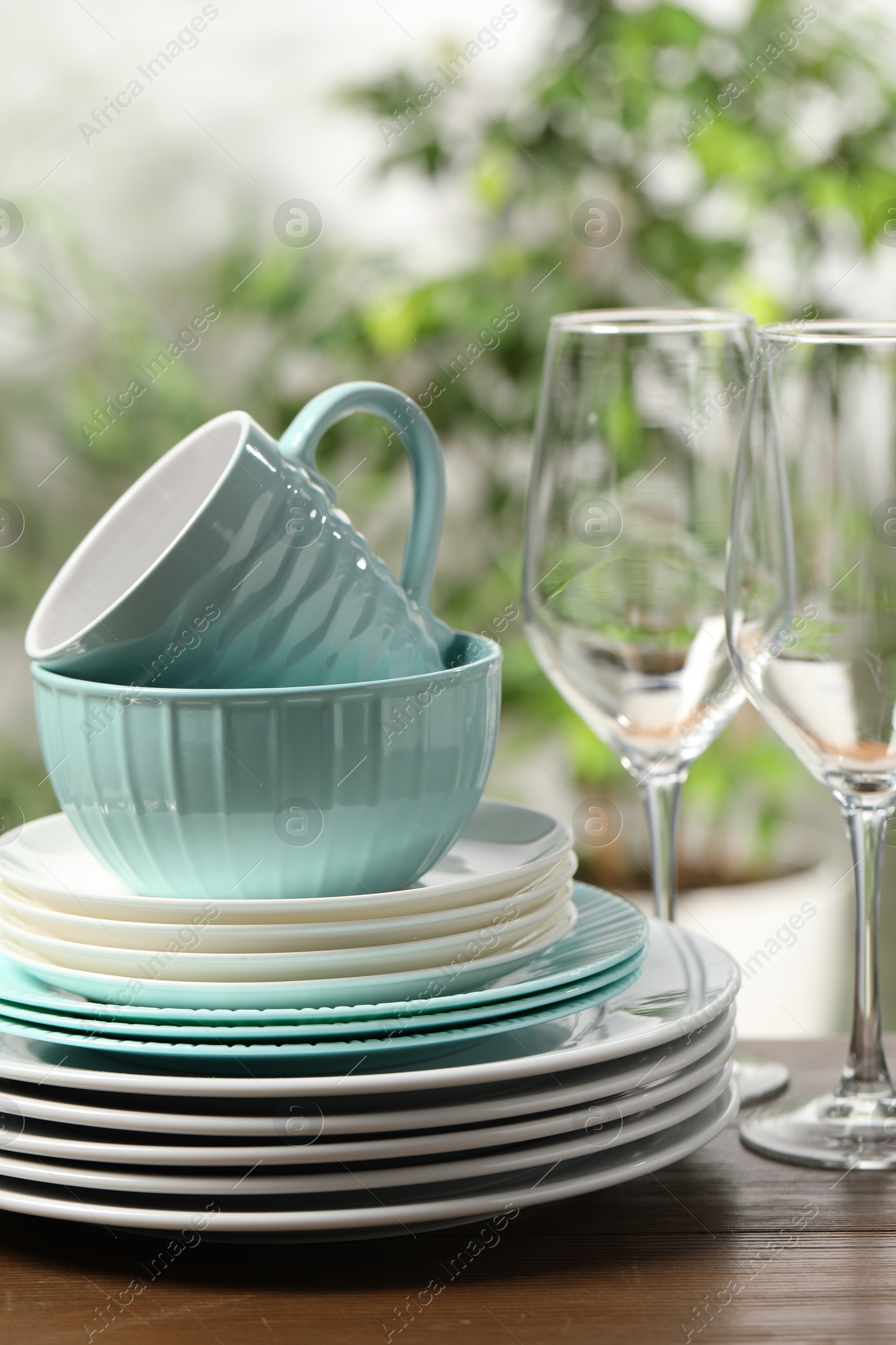 Photo of Beautiful ceramic dishware, glasses, cutlery and cup on wooden table outdoors