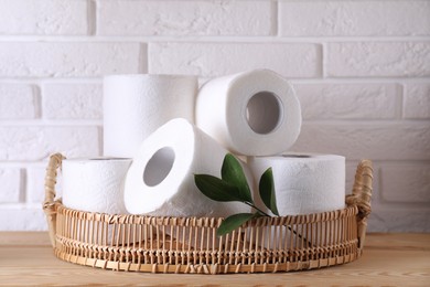 Photo of Toilet paper rolls and green leaves on wooden table near white brick wall