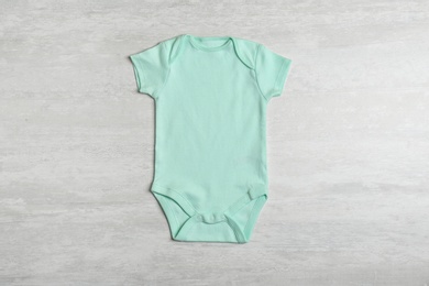 Photo of Baby bodysuit on wooden background, top view