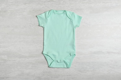 Baby bodysuit on wooden background, top view