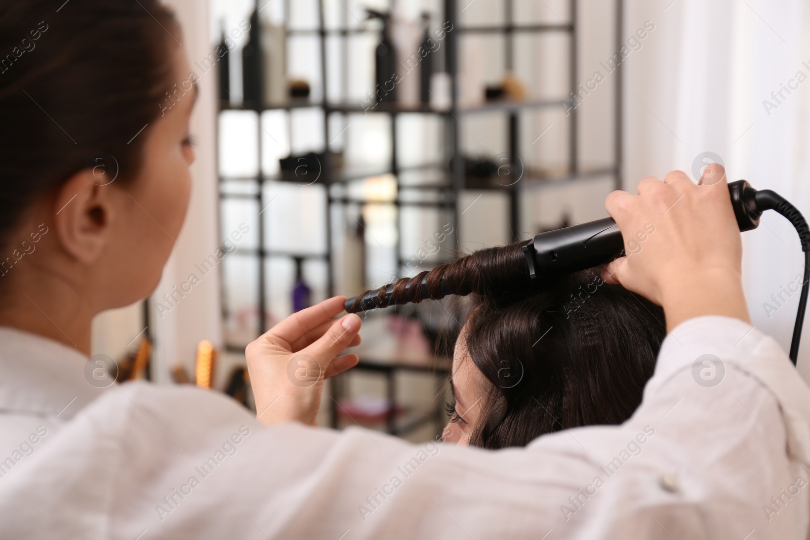 Photo of Stylist working with client in salon, making hairstyle