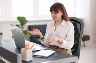Photo of Woman using video chat during webinar at table in office